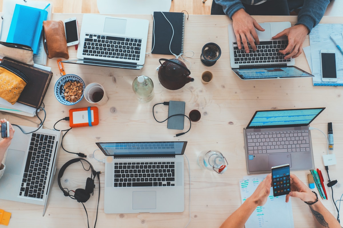 Multiple laptops open on a desk showing code